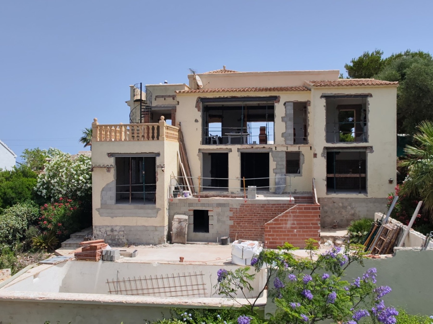 Casa Aikido under construction: the house opened up, new openings and brick walls, pool shell in the foreground